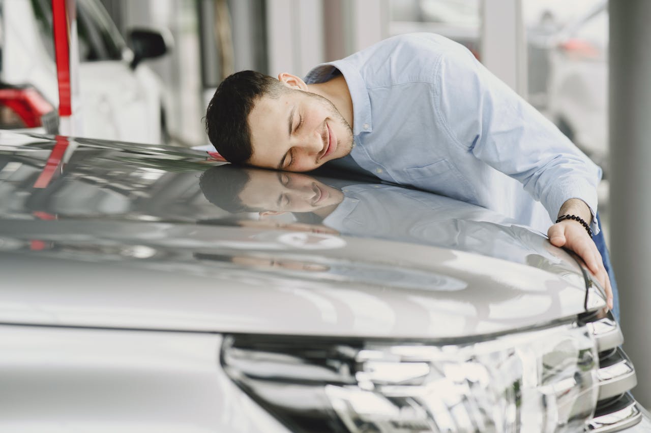 A man joyfully embracing a new car indoors, reflecting happiness and satisfaction.
